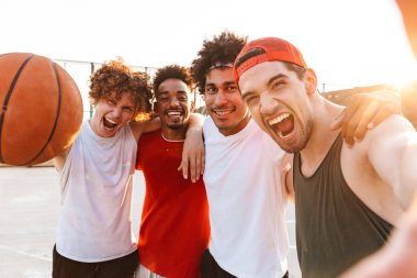 Sportif erkekler basketbol oyun alanı açık yaz güneşli gün boyunca oynarken top ve alma selfie tutan gülümseyerek, fotoğraf portre