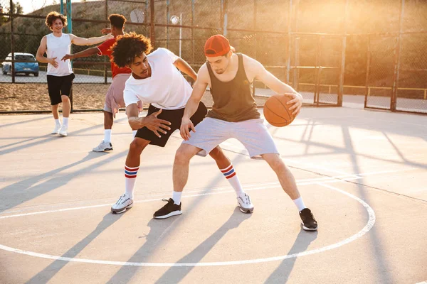 Group of young multiethnic men basketball players playing basketball at the sport ground