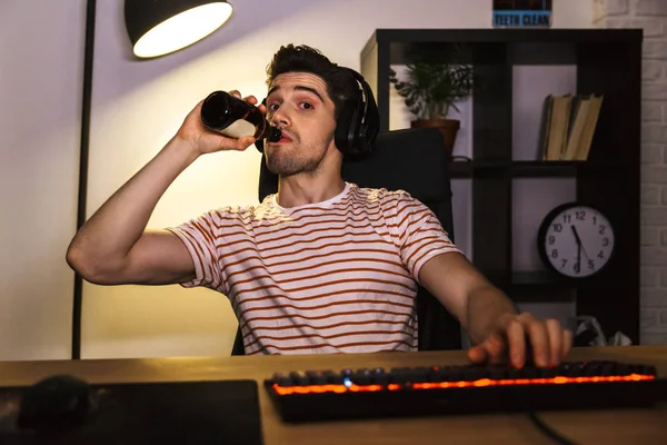 Retrato Jugador Caucásico Con Auriculares Bebiendo Cerveza Mientras Está Sentado —  Fotos de Stock