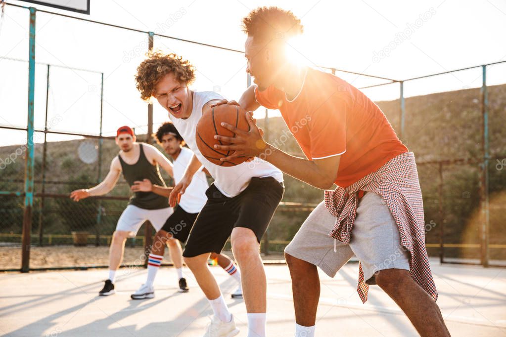 Group of young strong multiethnic men basketball players playing basketball at the sport ground
