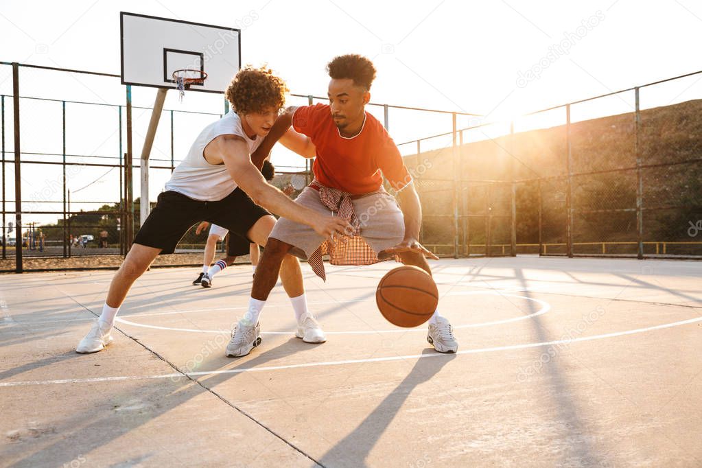 Group of young sporty multiethnic men basketball players playing basketball at the sport ground