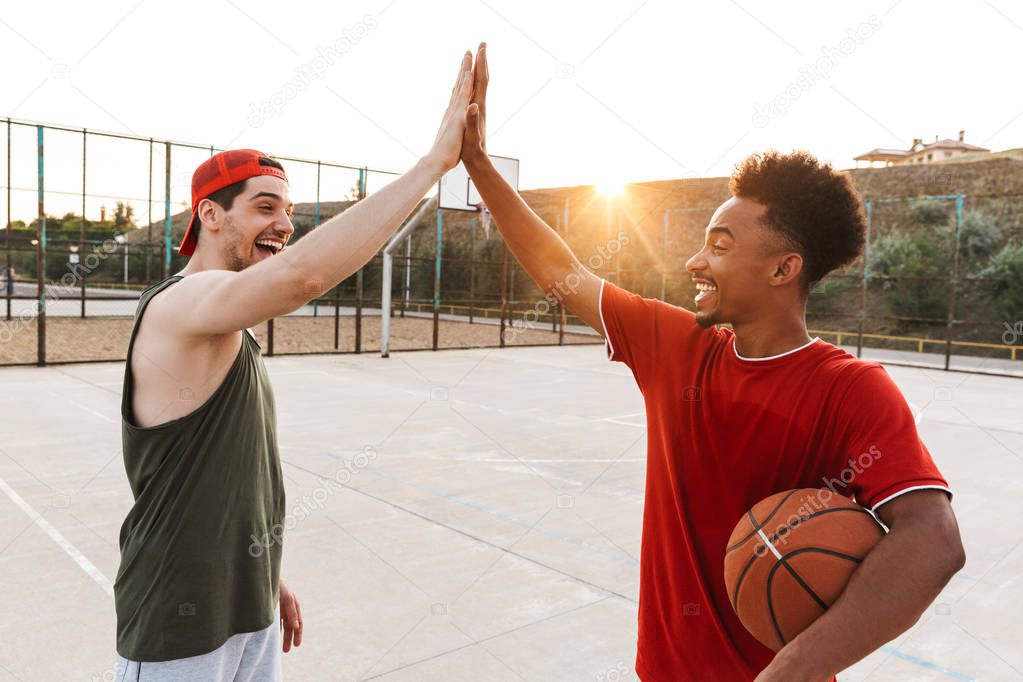 Portrait of energetic sporty boys playing basketball at the playground outdoor during summer sunny day
