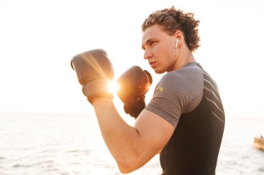 Fotoğraf genç yakışıklı erkek boxer plaj boks eldiven üzerinde açık havada spor.
