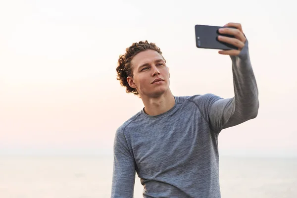 Serious Curly Sportsman Fazendo Selfie Smartphone Enquanto Está Praia Perto — Fotografia de Stock