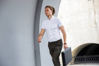 Evrak Çantası'nı uzak sokakta yürürken seyir ile sakin kıvırcık iş adam resmi