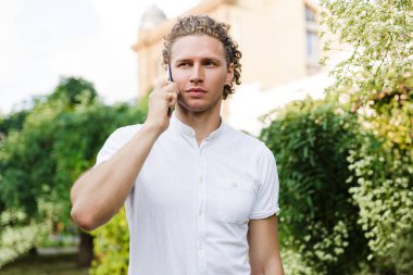 Smartphone ile konuşmak ve uzak duran sokakta arıyorum ciddi kıvırcık iş adamı