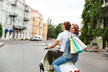Arkadan görünüşü ile paketleri açık havada retro scooter sürme genç güzel çift