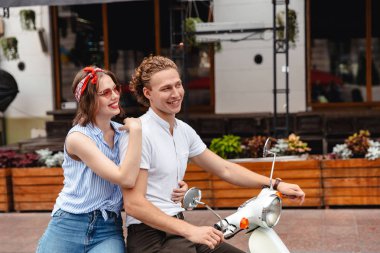 Gülümseyen genç bir çift şehir sokak birlikte bir motosiklet sürme portresi