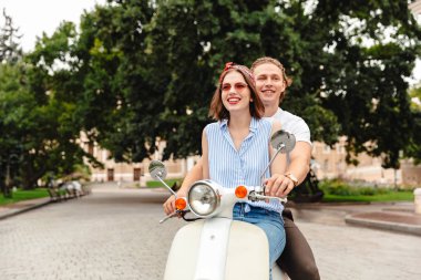 Gülümseyen genç bir çift şehir sokak birlikte bir motosiklet sürme portresi