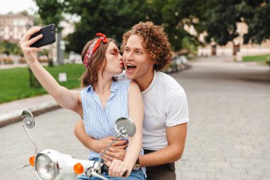 Portre pozitif bir genç çiftin bir selfie alarak şehir sokak birlikte bir motosiklet sürme