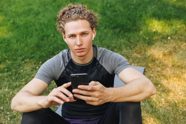 Bonito Jovem Desportista Ouvir Música Com Fones Ouvido Enquanto Sentado — Fotografia de Stock