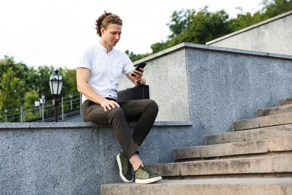 Tranquilo Hombre Negocios Rizado Con Maletín Usando Teléfono Inteligente Mientras — Foto de Stock