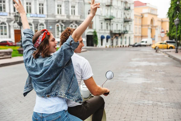 街で一緒にバイクに乗って陽気な若いカップルのビューの肖像画をバックアップします — ストック写真