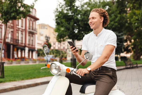 Sorridente Uomo Affari Riccio Che Tiene Smartphone Distoglie Sguardo Mentre — Foto Stock