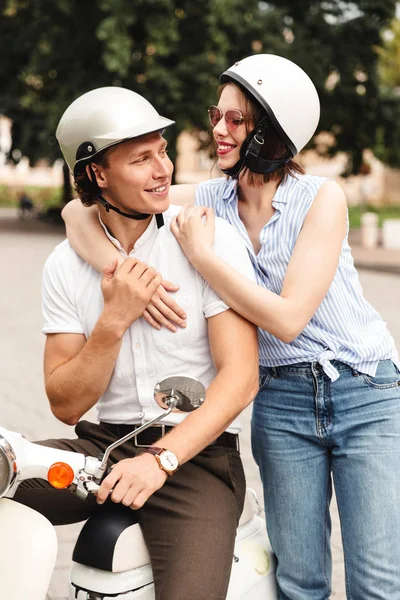 Happy young couple together on motorbike at the city street, laughing
