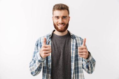 Başparmak gösterilmesini beyaz üzerinde izole bir gülümseyen Genç sakallı adam ayakta portresi