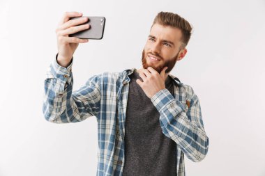 Bir selfie alarak üzerinde beyaz, izole bir neşeli Genç sakallı adam ayakta portresi