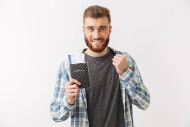 Pasaport bilet uçan ile gösterilen beyaz üzerinde izole bir neşeli Genç sakallı adam ayakta portresi