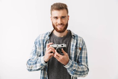 Vintage kamerayı beyaz üzerinde izole bir kendine güvenen genç sakallı adam ayakta portresi