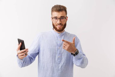 Cep telefonu tutan bir gülümseyen Genç sakallı adam beyaz üzerinde izole ayakta gözlük portresi