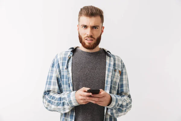 Retrato Joven Barbudo Confuso Parado Aislado Sobre Blanco Sosteniendo Teléfono — Foto de Stock