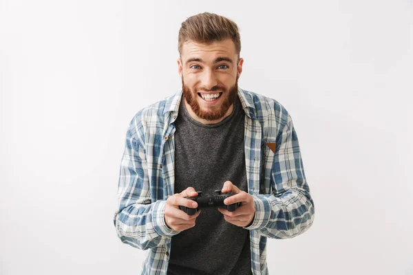 灰色の背景の上にカメラを見ながらジョイスティックでビデオゲームのシャツで幸せなひげを生やした男 — ストック写真