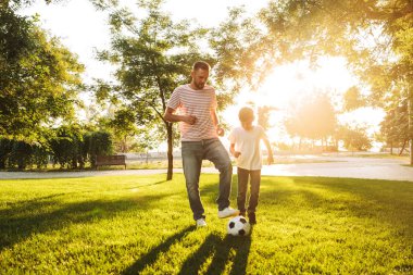 Mutlu baba oğluyla bir çim futbol oynarken küçük parkta, vakit