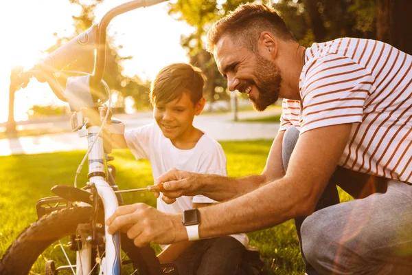 Feliz Padre Hijo Divirtiéndose Juntos Parque Verde Arreglando Bicicleta Juntos — Foto de Stock