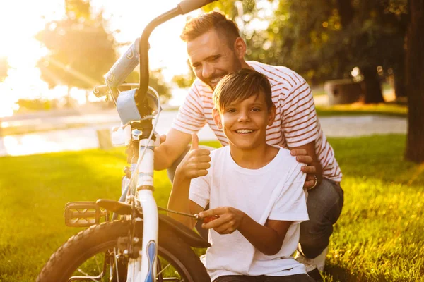Riendo Padre Hijo Divirtiéndose Juntos Parque Verde Arreglando Bicicleta Juntos — Foto de Stock