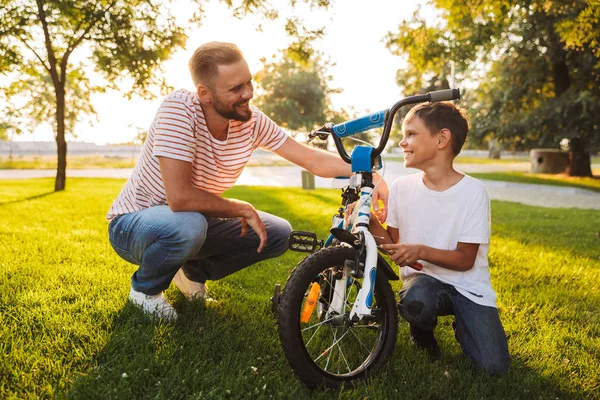 Joven Padre Hijo Divierten Juntos Parque Verde Arreglando Bicicleta Juntos — Foto de Stock