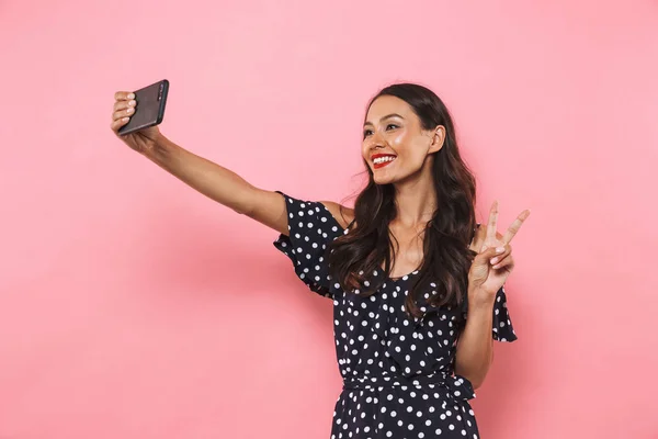 Smilende Brunette Kvinde Kjole Gør Selfie Smartphone Viser Fred Gestus - Stock-foto