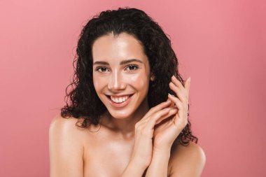 Genç ve güzel bir üstsüz kadın kıvırcık esmer saçlı pembe arka plan üzerinde poz Güzellik Portresi