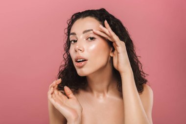 Genç, sağlıklı bir üstsüz kadın kıvırcık esmer saçlı pembe arka plan üzerinde poz Güzellik Portresi