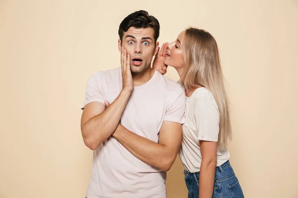 Portrait Shocked Young Couple Standing Together Beige Background Telling Secrets — Stock Photo, Image