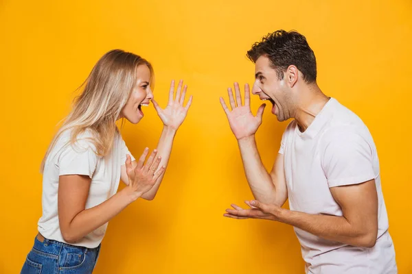 Photo Displeased Young Loving Couple Screaming Standing Isolated Yellow Wall — Stock Photo, Image
