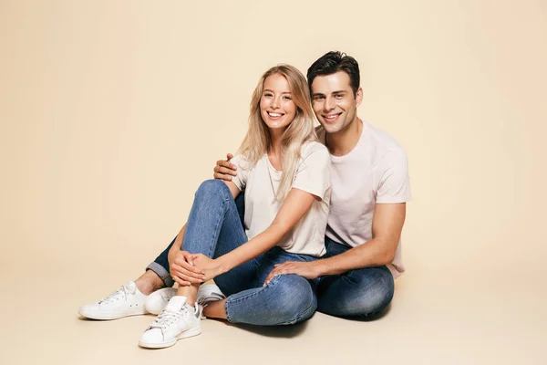 Retrato Una Feliz Pareja Joven Sentados Juntos Sobre Fondo Beige — Foto de Stock