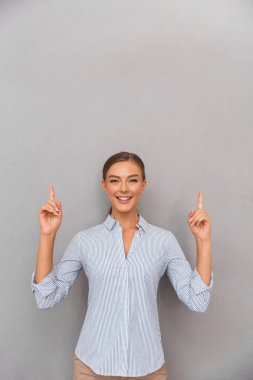 Boşaltmak için işaret poz gri duvar arka plan üzerinde duran mutlu iş kadın görüntüsünü.