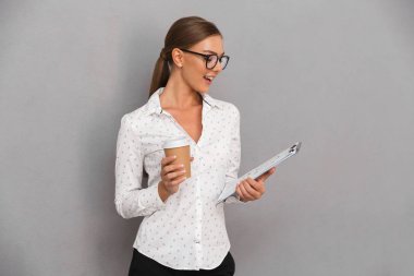 Kahve içme gri duvar arka plan holding Pano üzerinde duran güzel iş kadın görüntüsünü.