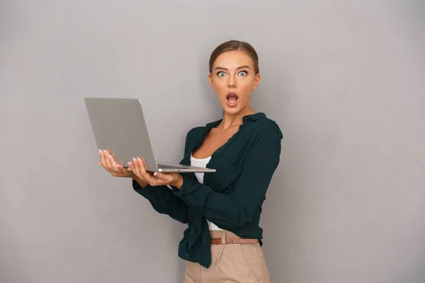 Sorprendido Joven Empresaria Pie Sobre Fondo Gris Trabajando Ordenador Portátil — Foto de Stock