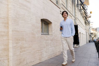 Yakışıklı genç casual adam şehir sokak yürürken cep telefonu tutan