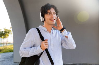 Kulaklık ile müzik dinlemek mutlu iş adamı şehir sokak sırt çantası taşıyan gömlek giymiş