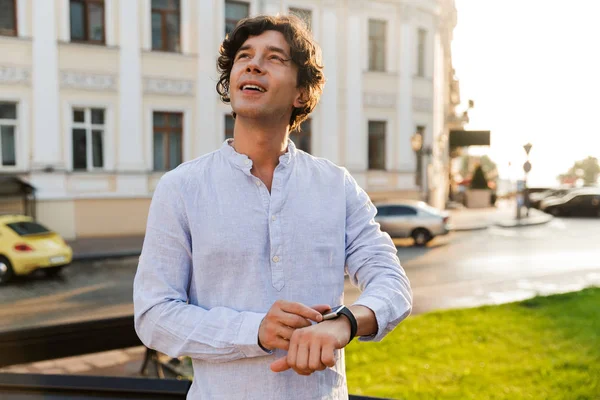 Joven Alegre Hombre Casual Ajustando Reloj Inteligente Mientras Camina Por — Foto de Stock