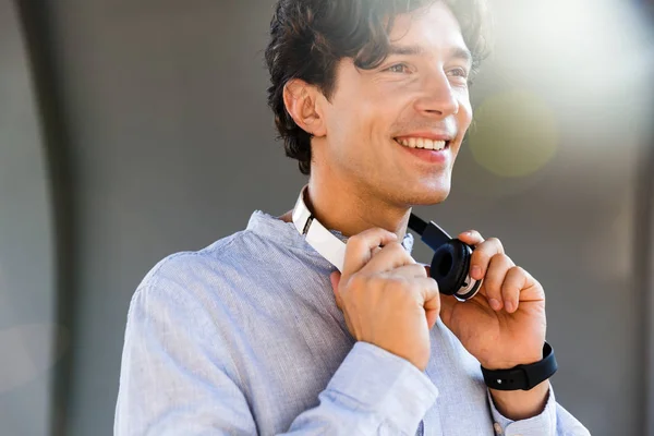 笑年轻的休闲男子与耳机站在城市街道 — 图库照片