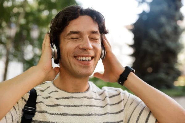 快乐的休闲男子背着背包在城市街 听音乐与耳机 — 图库照片