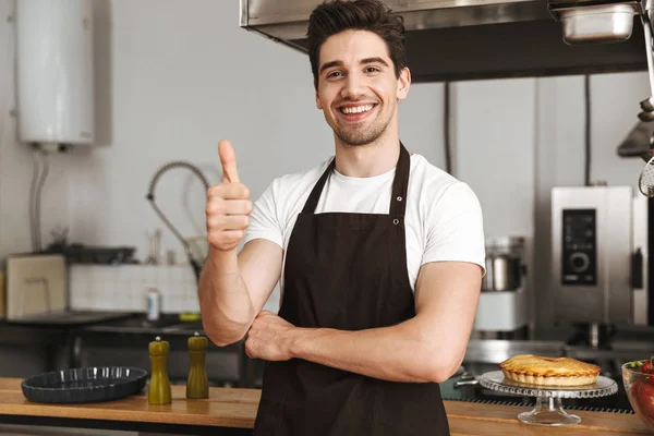 Šťastný Mladý Muž Kuchaře Vařit Zástěře Stojí Kuchyni Ukazuje Palec — Stock fotografie