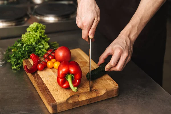 Close up of a man chef hands chopping vegetables on a cutting board at he kitchen