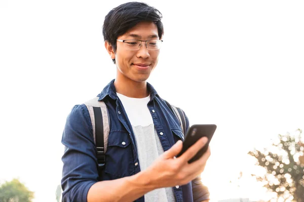 Glada Asiatisk Manlig Student Glasögon Med Smartphone Medan Sitter Park — Stockfoto
