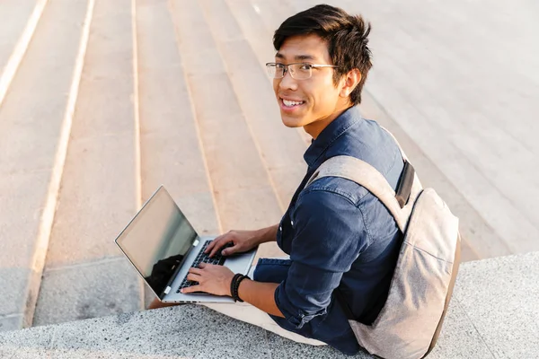 Vrolijke Aziatische Man Student Met Rugzak Laptopcomputer Zittend Buiten Gebruikt — Stockfoto