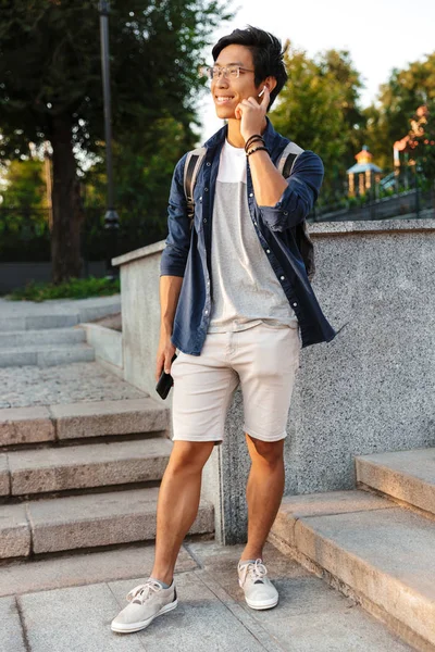 Longitud Completa Imagen Alegre Asiático Macho Estudiante Gafas Hablando Por — Foto de Stock