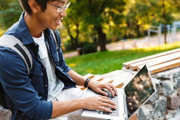 Widok Boku Smiling Asian Student Mężczyzna Okularach Pomocą Laptopa Siedząc — Zdjęcie stockowe